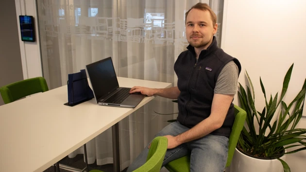 Bild på William Fransson sittande vid skrivbord med laptop framför sig