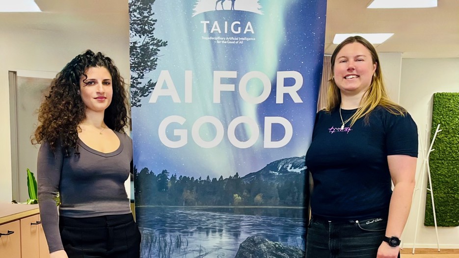 Two women on each side of a TAIGA rollup