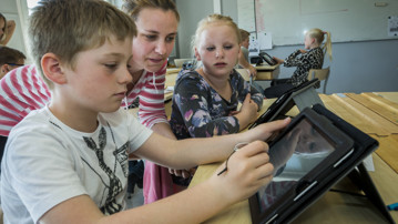 Barn i klassrum använder surfplatta.