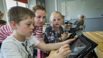 Barn i klassrum använder surfplatta.