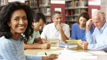 Mogna studenter i ett bibliotek för att illustrera livslångt lärande.