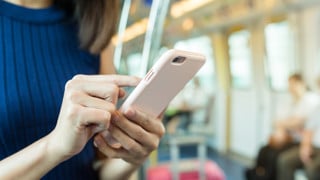 Person i tågvagn som surfar på mobiltelefonen.