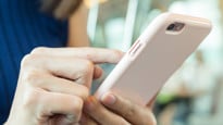 Person i tågvagn som surfar på mobiltelefonen.