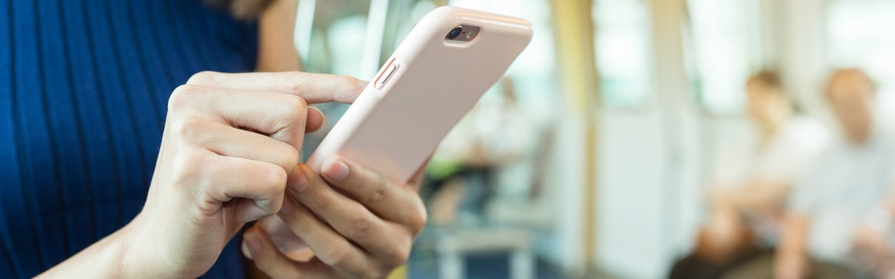 Person i tågvagn som surfar på mobiltelefonen.