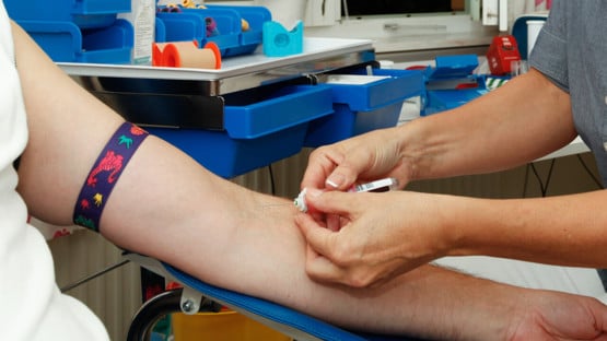 Närbild på sjukvårdspersonal som tar blodprov på en patient.