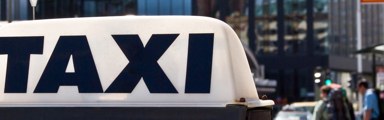 Taxibilar i Stockholm. Detalj med taxiskylt på biltaket i förgrunden.