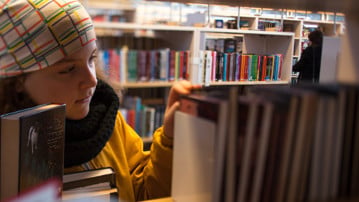 Flicka i 10-årsåldern letar böcker på bibliotek.