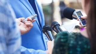 Närbild på mikrofoner och inspelningsutrustning när journalister intervjuar en person i samband med en presskonferens. Genrebild.