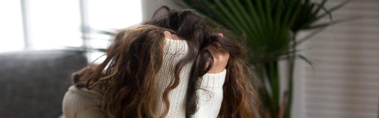 Kvinna som döljer sitt ansikte i sina händer. Ska illustrera psykisk ohälsa, depression, nedstämdhet eller liknande.