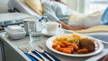 Sängliggande patient har fått en bricka med mat serverad på ett sjukhus.