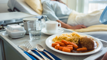 Sängliggande patient har fått en bricka med mat serverad på ett sjukhus.