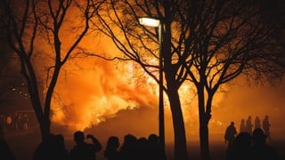 Flammor från intensiv skogsbrand med mänskliga silhuetter i förgrunden