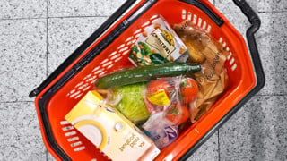 Varukorg med matvaror står på butiksgolv.