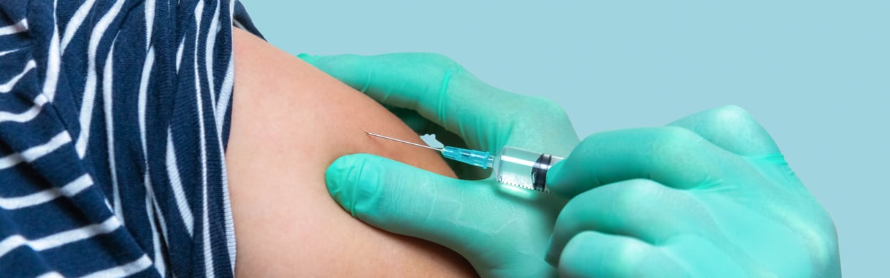 Handskbeklädda händer ger spruta med vaccin på en arm.