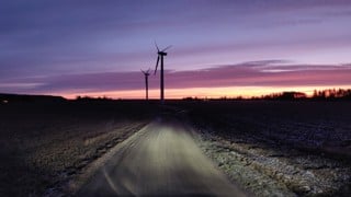 Vindkraftverk i tidig gryning och en bilväg.
