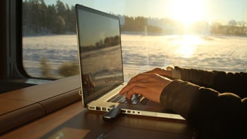 Bild på person med laptop på tåg