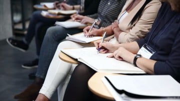 Detaljbild på konferensdeltagare som gör anteckningar.