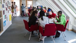 En grupp skolelever på högstadiet sitter vid ett bord och äter mat.