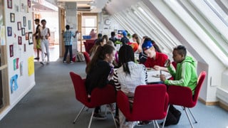 En grupp skolelever på högstadiet sitter vid ett bord och äter mat.