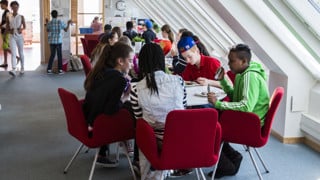 En grupp skolelever på högstadiet sitter vid ett bord och äter mat.