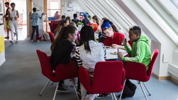 En grupp skolelever på högstadiet sitter vid ett bord och äter mat.
