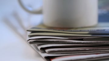 Hög med tidningar och en kaffekopp.