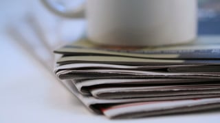 Hög med tidningar och en kaffekopp.