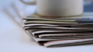Hög med tidningar och en kaffekopp.