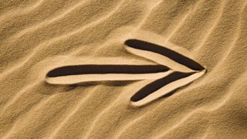 Pil ritad i sand.