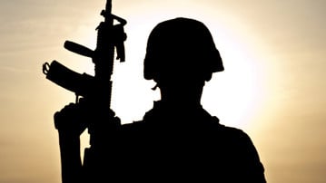 Siluett av en soldat i militärhjälm i motljus.
