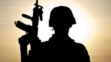 Militär med vapen i motljus