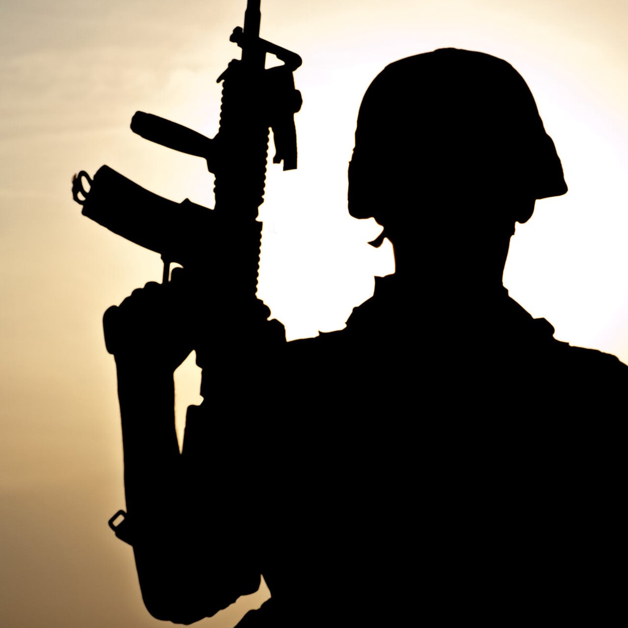 Siluett av en soldat i militärhjälm i motljus.