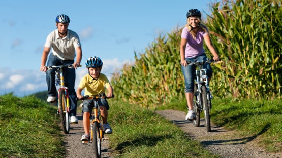En familj med mamma, pappa och barn cyklar.