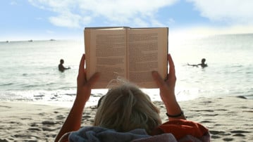Bild på bokläsare på strand