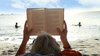 Bild på bokläsare på strand