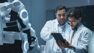Bilden visar forskare som står framför en robot.