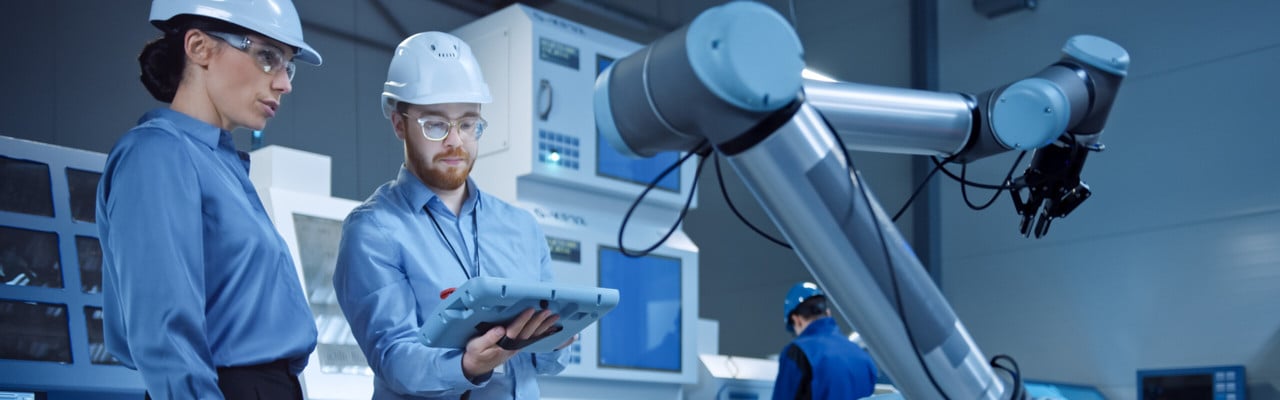 Bilden visar en kvinna och en man som arbetar med en robot.