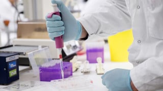 Photo of hand holding pipette in a chemistry lab