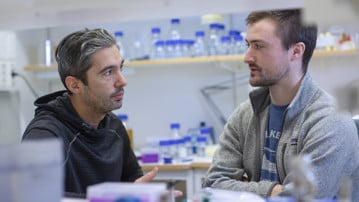 Bakom hylla med provrör står Felipe och Michael