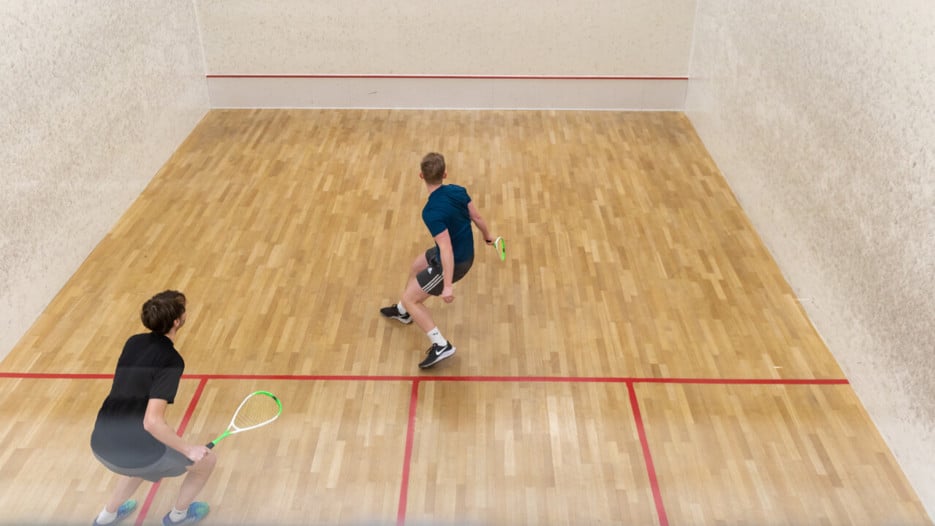 Två killar spelar squash.