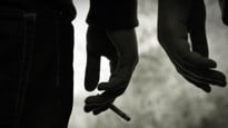 Närbild på hand som håller cigarett.
