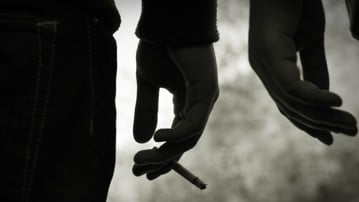 Närbild på hand som håller cigarett.
