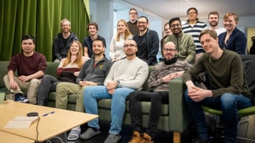 Gruppbild på ett 15-tal glada personer inomhus.