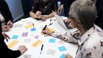 Bord med post-it-lappar och grupp människor.