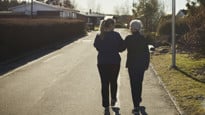 Äldre och yngre kvinna promenerar bort från fotografen