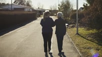 Äldre och yngre kvinna promenerar bort från fotografen