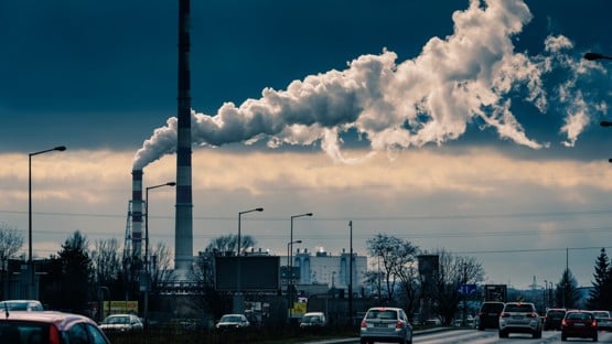 Bilar och rök från skorstenar i industriområde.