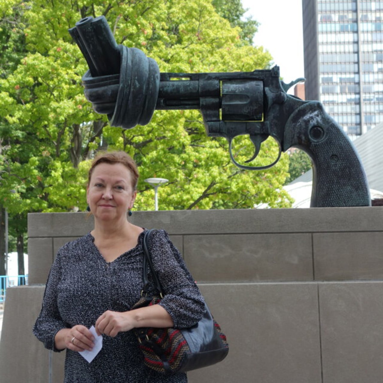 Maria Nilsson poserar framför en skulptur på en knuten revolver utanför FN-skrapan i New York