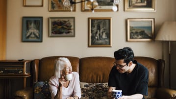 Yngre man och äldre kvinna dricker kaffe