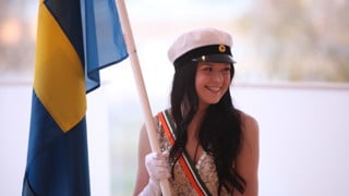 Studentmarskalk som håller en flagga vid Vårpromotionen.